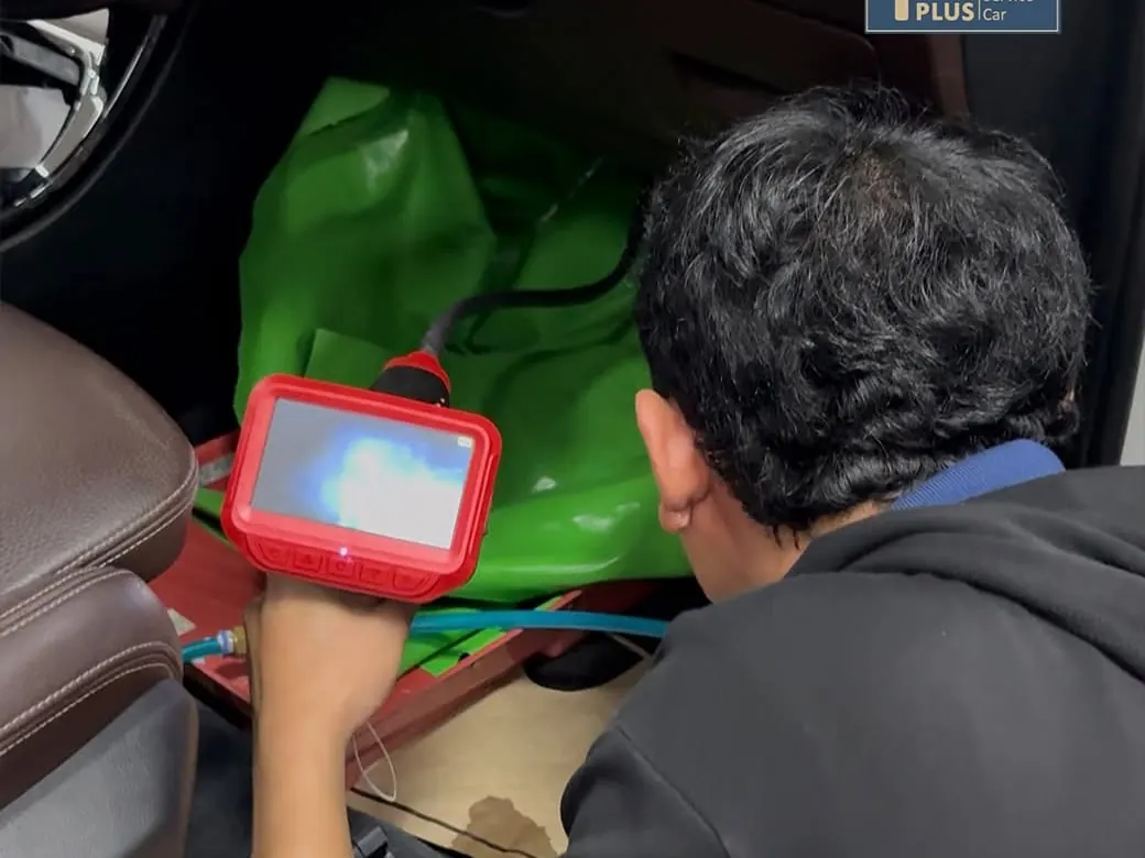 ช่างของ P-Plus BM Service ใช้เครื่องมือวินิจฉัยแบบพกพาตรวจระบบภายในห้องโดยสารรถ BMW พร้อมปูผ้าคลุมกันเปื้อน